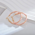 Elegante goldene Ohrringe mit rosa Emaille-Textur auf weißem strukturiertem Grund - Rosa