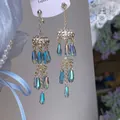 Détail de boucles d'oreilles à pompons dorés avec cristaux et strass brillants - Or et Bleu (7#)