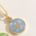 Macro d'un pendentif doré avec mosaïque en nacre bleue et détail de cœur en zircon - Bleu royal