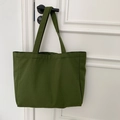 Detail of forest green canvas tote bag showing stitching quality on a door handle - Solid Army Green