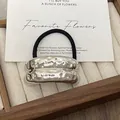 Silver hammered metal hair cuff with black elastic tie on a wooden jewelry display tray - GD429 Silver Wrinkle Double Arc