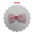 Pink tulle bow hair accessory with woven center knot on a white decorative card display - Champagne
