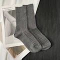 Grey ribbed knit cotton mid-calf socks displayed over magazines on a pleated fabric backdrop - Short Dark Grey
