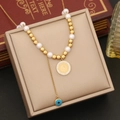 Dettaglio collana di perle con ciondolo a moneta e occhio greco su vassoio vintage - Collana
