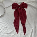 Elegant wine red bow hair clip with long ribbons on soft white textured background - Burgundy