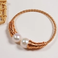 Handmade gold wire wrap bangle with two lustrous freshwater pearls on white surface - Handmade Gold Wire Wrapped Bangle