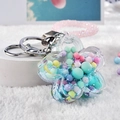 Close-up of acrylic flower keychain with colorful macaron beads and glitter filling - Green