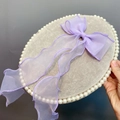 Nahaufnahme eines Samt-Schmucktabletts mit Perlenrand und einer großen Organza-Schleife - Helllila