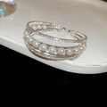 Makrodetail eines mehrlagigen Perlenarmbands mit schimmernden Zirkonia auf Silbermetall - Silberne dreilagige Kette Stil