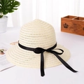 Detailed view of beige straw sun hat featuring a black ribbon bow and hollow weave. - White
