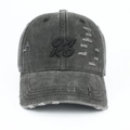 Détail de casquette de baseball délavée gris foncé avec trous usés et broderie OKKO - Noir
