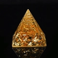 Pyramid energy orgone with golden foil flakes and spiral metal coil on black background - Citrine