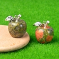 Green and red natural stone apple pendants with silver metal leaf charms on wood - Unakite