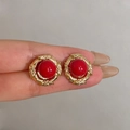 Vintage style gold earrings with red round stone inlay held in fingers for scale - Vintage Red Stone Gold Rim