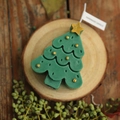 Handmade green Christmas tree candle with gold ornaments on a rustic wood base - Green Christmas Tree