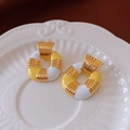 Detailed close-up of French-style gold square earrings on a decorative white dish - Gold Yellow White Square Color Block Style