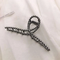 Macro detail of gunmetal grey hair claw clip with twisted texture on white fabric - Gunmetal Black-Twisted Cross