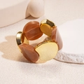 Dettaglio del bracciale con maglie in resina ambrata e metallo dorato su vassoio - Grigio Caffè