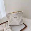Dettaglio del ricamo in pizzo floreale bianco su una borsa cosmetica in morbido cotone - Taglia Piccola