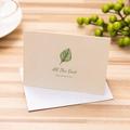 Elegant greeting card with green leaf motif and white envelope on wooden table - All The Best / With Envelope
