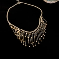 Nahaufnahme einer goldenen Quastenkette mit filigranem Metallnetz und Perlenfransen - Halskette - Gold