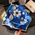 Dettaglio di un foulard in seta floreale con borsa bianca e accessori di lusso - Blu