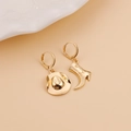 Detailed macro view of asymmetric golden alloy cowboy boot and hat hoop earrings - Asymmetric Cowboy Hat & Boot Earrings / Gold