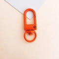 Close-up of orange painted metal lobster clasp for keychains and DIY bag accessories - Orange Red