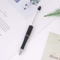 Retractable black and silver massage pen on a bright desk with natural decor - Black