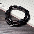 Close-up of black ebony barrel bead bracelet with Dzi bead on calligraphy scroll - Ebony 7X13mm Double Loop With Dzi Bead