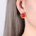 Vintage style gold earrings with red turquoise stone inlay shown on a model - Gold Red Turquoise Earrings