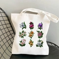 White canvas tote bag featuring nine colorful floral prints on a black metal chair - STD704-B Fresh Flowers