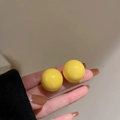 Close-up of bright yellow round stud earrings held by hand against a soft background - Bright Yellow Glazed Ball Stud Earrings