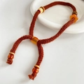 Primer plano del collar trenzado marrón con cuentas de ámbar y colgante de corazón de madera - Estilo de Cuentas Marrón