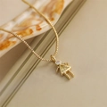 Macro detail of a golden necklace with a girl-shaped pendant and yellow crystal stone - August Yellow