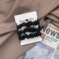Set of 3 black satin scrunchies with Sweet Girl card on stylish newspaper background - Black