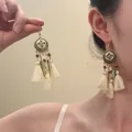 Detail of vintage gold flower earrings with wooden beads and long cream cotton tassels - Retro Gold Leaf Wood Bead Tassel Style / 8# Ear Hook - Gold - Purple - White