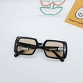 Flat lay of black square hip-hop sunglasses with brown lenses on white background - Black Frame Tea Lens