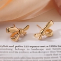 Élégantes boucles d'oreilles nœud dorées sur fond papier et tissu rose doux - Petit Style Stéréoscopique / Doré