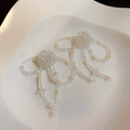 Nahaufnahme von süßen Perlenohrringen mit Schleifen auf einem Keramiktablett - Schleife Quaste Transparent Stil / Transparent