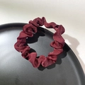 Detailed close-up of a deep red satin scrunchie placed on a black round tray - Burgundy
