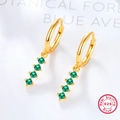 Detailed macro view of 925 sterling silver gold earrings with emerald green gemstones - Gold/Green