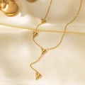Elegante collana cuore in titanio dorato con quattro ciondoli 3D su sfondo di seta - Solo Collana a Cuore / Oro