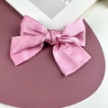 Pink satin bow hair clip with a smooth ribbon finish on a pink display mat - Sakura Pink (Spring Clip)