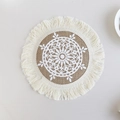 Handwoven jute placemat with white floral pattern and beige fringe trim in boho style - Type A Jute Coaster