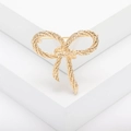 Elegante spilla a fiocco dorata con trama intrecciata su un supporto bianco pulito - Oro