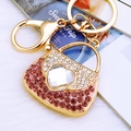 Pink rhinestone handbag keychain with heart crystal and golden clasp on plush backdrop - Purple Heart Handbag Keychain