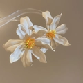 Close-up of oversized white acrylic flower earrings with yellow beaded centers - Silver Needle (White) / White