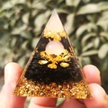 Orgone crystal pyramid with obsidian, gold foil and lotus, held against green foliage - Pink Leaf Lotus Gold Foil / Small