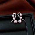 Detailaufnahme von silbernen Schleifenohrringen mit Zirkonia und drei violetten Perlen - Silberner Ohrstecker - Silber - Rosa